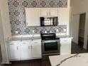 Modern kitchen featuring white cabinetry, black appliances, and stunning tile backsplash at 8415 S 47Th Ln, Laveen, AZ 85339