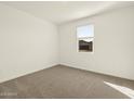 A bright and airy bedroom with neutral carpet, a window providing natural light, and minimalist decor at 4958 W Hunter Trl, San Tan Valley, AZ 85144