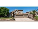 House exterior showcasing stone accents, a three-car garage, and mature trees at 1622 E Nighthawk Way, Phoenix, AZ 85048
