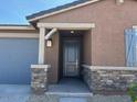 Close-up of front door featuring stone accents, a covered porch, and a gray door with sidelight at 20293 N 225Th Dr, Surprise, AZ 85387