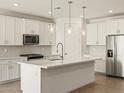 Modern kitchen with white cabinets, a large island, stainless steel appliances, and stylish pendant lighting at 20357 N 225Th Dr, Surprise, AZ 85387