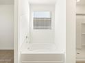 Clean bathroom with a built in tub and window at 37406 W San Clemente St, Maricopa, AZ 85138