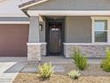 Inviting front entrance with stone accents, a dark wood door, and professionally landscaped yard at 20331 N 225Th Dr, Surprise, AZ 85387