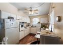 Cozy kitchen with white cabinets, vintage appliances, wood-look flooring, and ample natural light at 11038 W Windsor Dr, Sun City, AZ 85351