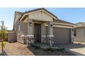 Charming single-story home with stone pillar accents, a brown garage door and well kept landscaping at 5678 N 205Th Ln, Buckeye, AZ 85396