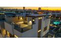 A modern townhome showcases a rooftop patio with dining set against a vibrant city skyline at sunset at 377 E Windsor Ave # 21, Phoenix, AZ 85004