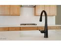 Close-up of a kitchen island with granite countertops, wooden cabinets, and a black faucet at 4799 W Flat Iron Ct, Queen Creek, AZ 85144