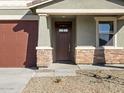 Front entry of home with brown door and stone accents at 16014 W Cottontail Ln, Surprise, AZ 85387