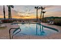 Community pool featuring a sunset view, palm trees, lounge chairs, and serene desert mountain views at 10401 N Saguaro Blvd # 224, Fountain Hills, AZ 85268