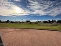 Scenic view of a lush green community space under a bright blue sky with scattered clouds at 3202 E Decatur St, Mesa, AZ 85213