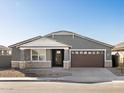 Two-story house with gray exterior, brown garage door, and stone accents at 36933 W La Paz St, Maricopa, AZ 85138