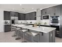 Stylish kitchen featuring gray cabinets, stainless steel appliances, and a central island with bar seating at 25137 N 171St Ave, Surprise, AZ 85387