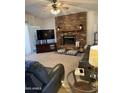 Cozy living room featuring a brick fireplace, ceiling fan, comfortable leather seating, and neutral carpeting at 402 W Grandview Rd, Phoenix, AZ 85023