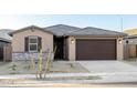 Charming single-story home features a brown two-car garage and a low maintenance gravel front yard at 22455 W Pontiac Dr, Surprise, AZ 85387