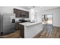 Modern kitchen features stainless steel appliances, gray cabinets, granite countertops, and a center island with a sink at 24593 W St Catherine Ave, Buckeye, AZ 85326