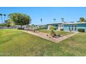 Community outdoor patio with dining, lush green lawn, mature trees, and well-maintained landscaping at 10026 W Lancaster Dr, Sun City, AZ 85351