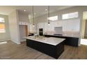 Modern kitchen with white cabinets, black island, stainless steel appliances, and wood-look tile flooring at 32513 N 135Th Dr, Peoria, AZ 85383