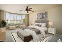 Staged primary bedroom with bay window, ceiling fan, and neutral decor at 2606 N 159Th Dr, Goodyear, AZ 85395