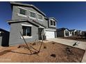 Two-story house with gray exterior, white garage door, and landscaping; other homes under construction at 4294 E Bradford Ave, San Tan Valley, AZ 85143