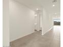 Bright hallway featuring neutral tile flooring, white walls, and access to a bathroom and views of the outdoors at 4937 W Hunter Trl, San Tan Valley, AZ 85144