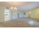 Spacious living room featuring neutral carpet, chandelier and a large window for natural light at 12442 W Marble Dr, Sun City West, AZ 85375