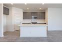 Modern kitchen with gray cabinets and a large island with white quartz countertops at 40000 W Bunker Dr, Maricopa, AZ 85138