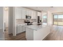 Bright, white kitchen featuring stainless steel appliances, ample counter space, and wood-look tile flooring at 18197 W Cielo Grande Ave, Surprise, AZ 85387