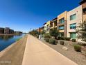 Scenic exterior of modern apartments with a pathway along the canal and a 'For Sale' sign at 4803 N Woodmere Fairway -- # 2006, Scottsdale, AZ 85251