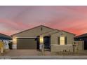 Tan house with brown garage door, black gate, and landscaping at dusk at 17738 W Coolidge St, Goodyear, AZ 85395