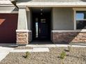 The house has a cozy front porch with stone veneer columns and a modern front door at 25975 N 160Th Ln, Surprise, AZ 85387