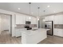 Bright kitchen with white cabinets, stainless steel appliances, a large island, and sleek gray backsplash at 18746 E Panchito Dr, Gold Canyon, AZ 85118