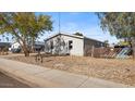 Gray single-story home with a gravel driveway and mature trees at 2612 E Sandra Ter, Phoenix, AZ 85032