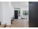 Bright entryway featuring sleek wood floors, modern light fixtures, and a stylish black front door at 10646 E Butherus Dr, Scottsdale, AZ 85255