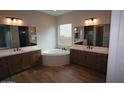 Spa-like bathroom featuring dual sinks, a soaking tub, and elegant tile work at 21553 W Pierson St, Buckeye, AZ 85396
