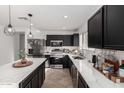 Modern kitchen with stainless steel appliances, waterfall island, and black cabinets at 8913 E Oro Cir, Mesa, AZ 85212