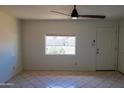 This inviting living room has neutral walls, tile floors, and a bright window with a peaceful view at 2007 N 67Th Dr, Phoenix, AZ 85035