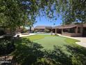 Expansive backyard with a pool, putting green, outdoor fire pit, and covered patio for exceptional outdoor living at 7801 E Davenport Dr, Scottsdale, AZ 85260