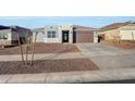 Modern single story home with a two car garage and minimalist landscaping with young trees in the front yard at 28958 N 174Th Ln, Surprise, AZ 85387