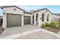 Inviting home featuring a stone driveway, a two-car garage, and an arched entryway at 17643 W Middlebury St, Surprise, AZ 85388