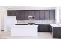 Stylish kitchen featuring dark cabinets, a white island, tile backsplash, and modern stainless steel appliances at 2445 W Rowel Rd, Phoenix, AZ 85085