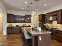 This open kitchen features dark wood cabinets, an island with seating, and stainless steel appliances at 2717 W Nighthawk Way, Phoenix, AZ 85045