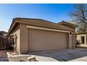 Tan house with a two-car garage and a stone accent wall at 5411 W Grenadine Rd, Laveen, AZ 85339