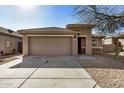 Tan colored house with a two-car garage and a gravel driveway at 5411 W Grenadine Rd, Laveen, AZ 85339