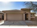 One-story house with tan colored exterior and a two-car garage at 5411 W Grenadine Rd, Laveen, AZ 85339