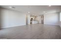 Spacious living room with ceramic tile flooring and recessed lighting, flowing into the kitchen area at 39980 W Bravo Dr, Maricopa, AZ 85138
