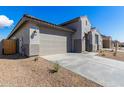 A garage and entryway are featured in the exterior view of a desert-landscaped modern home at 18440 W Monte Lindo Ln, Surprise, AZ 85387