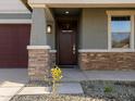 Close up of the front door and stone facade home exterior in the front yard at 16005 W Cottontail Ln, Surprise, AZ 85387