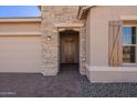 Front entrance with stone detailing and a brown door at 18955 W Ocotillo Rd, Waddell, AZ 85355