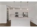 Bright kitchen with white cabinets, stainless steel appliances, a large island, and pendant lighting at 40005 W Elm Dr, Maricopa, AZ 85138