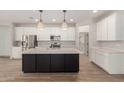 Modern kitchen features an island, stainless steel appliances, white cabinets, and stylish pendant lighting at 18428 W Robin Ln, Surprise, AZ 85387